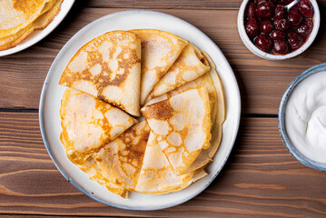 Homemade crepes pancakes with sour cream and cherry syrup