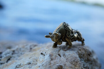 A bull figurine on the background of a river.