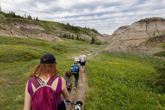 Family hiking along a trail with their dog in the Alberta Badlands on a Summer day