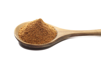 Pile ground, milled nutmeg powder in wooden spoon isolated on white, side view