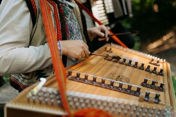 A musician performs on a traditional string instrument in a natural setting. Vibrant attire...