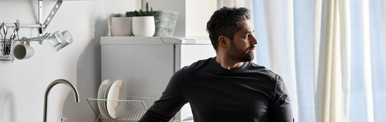 Fototapeta premium Handsome man enjoys a moment of reflection in a bright modern kitchen setting