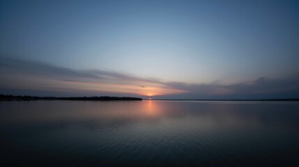 Obraz premium Serene Sunset Reflections Over Calm Lake Water at Dusk