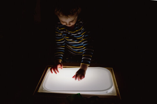 Child Exploring a Light Panel in the Dark