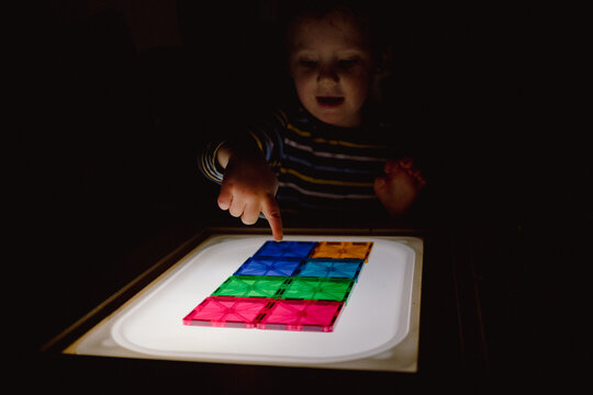 Child Pointing at Tiles on Light Panel