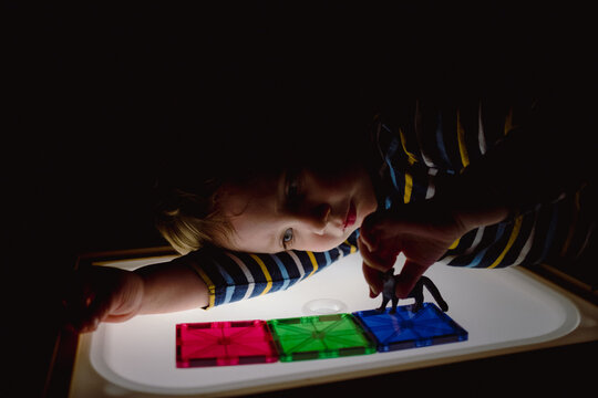Child Experimenting with Light Panel and Toy