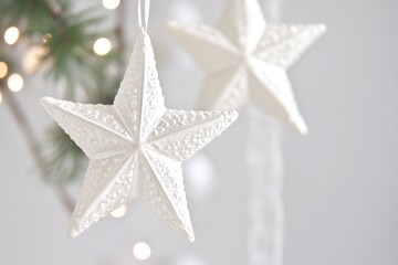 Two white star-shaped ornaments hanging from a Christmas tree