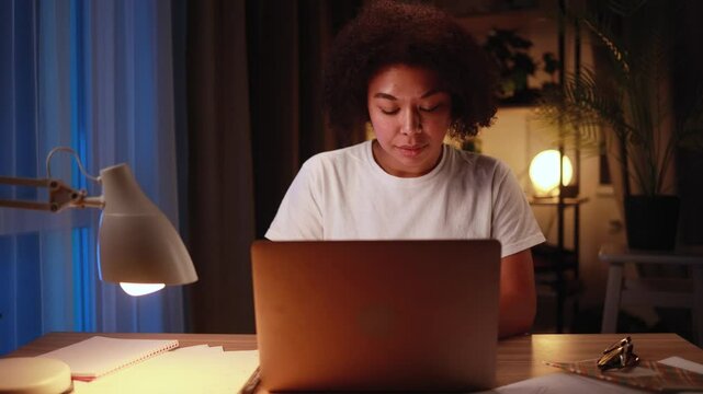 Pretty freelancer working on laptop checking email surfing web late at night indoors Focused young african american woman student having online distance education or work on computer at home workplace