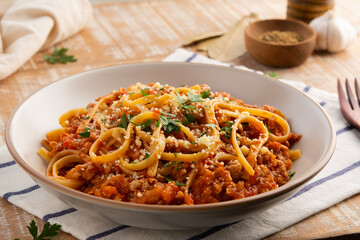 Homemade fettuccine spaghetti with Ground meat and tomato, pasta with a meat based bolognese tomatoes,served on white plate with parmesan cheese.