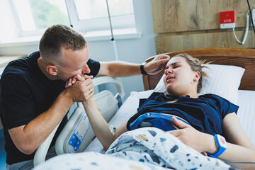 The beginning of labor in a young woman. Support for a man during labor. Partnered childbirth. Delivery room.