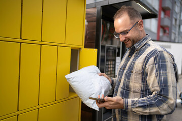 Man retrieves package from bright yellow locker in urban setting
