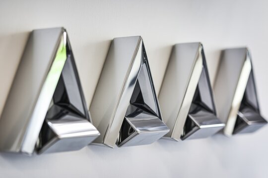 Sleek metallic triangular structures arranged in a row, possibly a modern art installation or architectural detail.