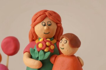 Playful clay figures of mother and child celebrating with flowers