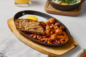 Vibrant Breakfast with Fried Eggs, Beans, and Meatballs in Rustic Composition