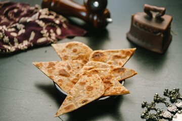 A platter holds freshly cooked parathas, golden brown and crispy, beautifully arranged with intricate ethnic decor accompanying them. This evokes a warm, inviting atmosphere
