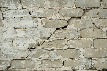 Old cracked brick wall close-up with weathered white plaster and uneven texture. Copy space. Background