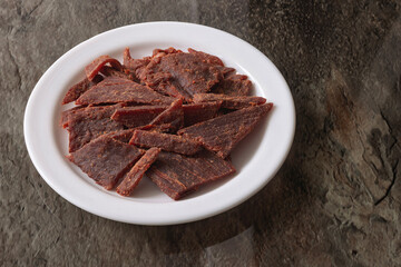Sweet and spicy beef jerky served on a white plate on the table