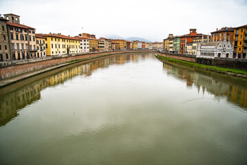 View on Arno river and colorful building, reflection in water, Pisa, Italy