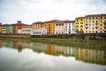 Fototapeta premium View on Arno river and colorful building, reflection in water, Pisa, Italy