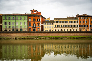 View on Arno river and colorful building, reflection in water, Pisa, Italy