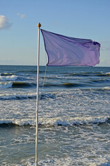 Signal purple beach flag against the background of the Baltic Sea