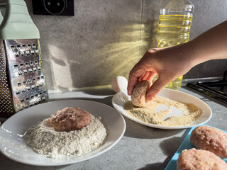 A woman's hand tears off pieces of minced meat and make cutlets