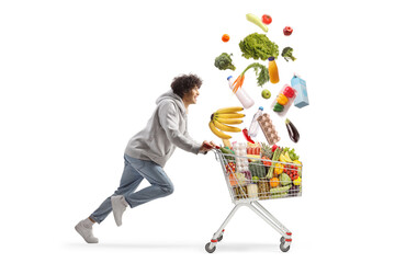 Young man running with falling food in a shopping cart, click and collect concept