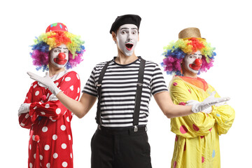 Mime posing with crossed arms in front of clowns