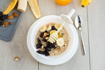 Healthy oatmeal with banana, nuts and prunes