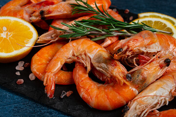 Freshly frozen shrimp, with lemon and rosemary, on black slate, close-up, top view, no people