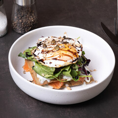 White plate of waffles and salmon with egg and seeds angle view