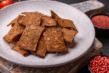 Crispy homemade brown bread chips with seeds and grains, salt, spices