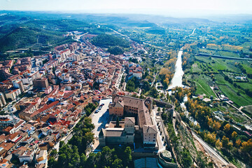 Aerial view of ancient town of Alcaniz, located in Teruel, Spain. Castle of the Calatravos, perched on hilltop, surrounded by historical buildings and modern urban structures