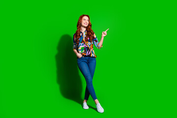 Stylish young woman posing confidently against bright green background, wearing colorful patterned blouse and jeans