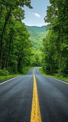 Obraz premium A paved road with a solid yellow line surrounded by dense green trees, leading to hills