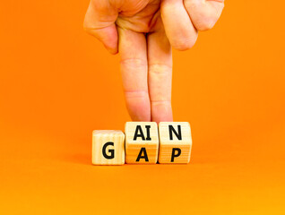 Gain or gap symbol. Concept words Gain Gap on wooden block. Beautiful orange table orange background. Businessman hand. Business gain or gap concept. Copy space.