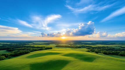 Fototapeta premium Expansive green landscape under a vibrant sunset sky with fluffy clouds