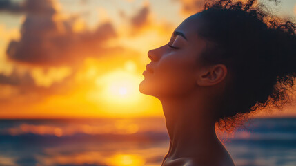 Woman practicing deep breathing exercises by the ocean at sunset to regain inner calm and mindfulness