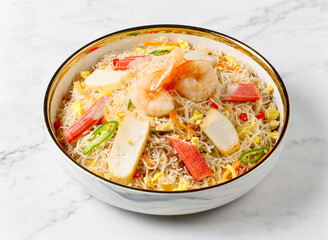 bee hoon goreng seafood with shrimp, crab sticks, and vegetables served in plate isolated on marble background side view of singapore food