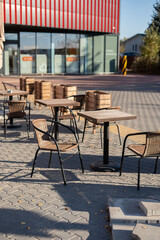 photo Outdoor seating area with wicker chairs and wooden tables on a sunny day, showcasing a relaxed and casual outdoor dining experience in a modern urban setting