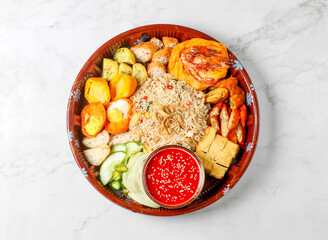 Malaysian Nasi Lemak Feast include coconut rice, sambal, fried anchovies, peanuts, cucumber, and hard boiled egg served in small bowl isolated on marble background side view of singapore food