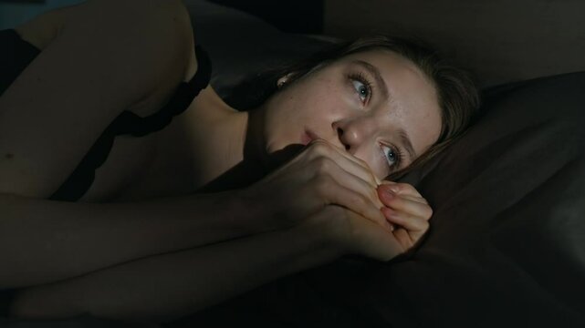 Close-up view of overwhelmed Caucasian girl with paranoid delusions having intense fearful feeling related to persecution or threat while lying on bed