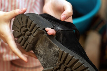 hand points through a hole in a worn-out shoe, highlighting the damage. The image captures the...