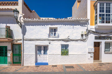 Nerja town, a resort of The Costa del Sol seaside region in Andalusia in the south of Spain. Whitewashed houses line a sun-drenched street, showcasing traditional architecture and vibrant colors.