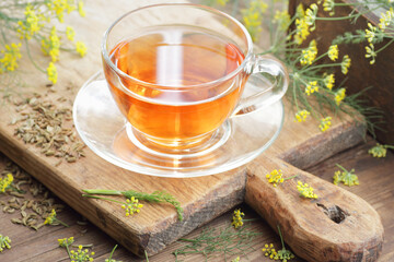 Fennel seed tea or extract on wooden background with fresh flowers nearby, copy space, natural medicine, drink for breast milk production, sleep and stress care tea concept