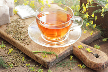 Fennel seed tea or extract on wooden background with fresh flowers nearby, copy space, natural medicine, drink for breast milk production, sleep and stress care tea concept