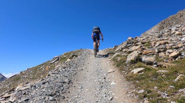 A man is riding a bike down a rocky mountain trail