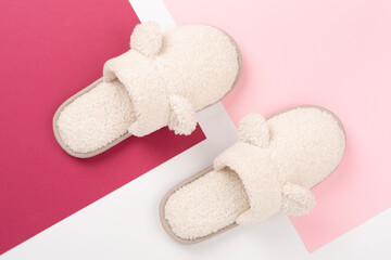 Soft teddy slippers on color background, top view