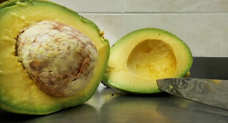 A fresh and vibrant image of an avocado (also known as 'palta') cut in half, showcasing the creamy green flesh and the large seed in the center. The smooth texture of the avocado is clearly visible