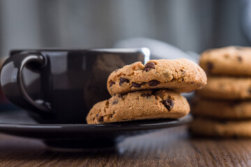 Chocolate chip cookies and coffee cup on wooden table.